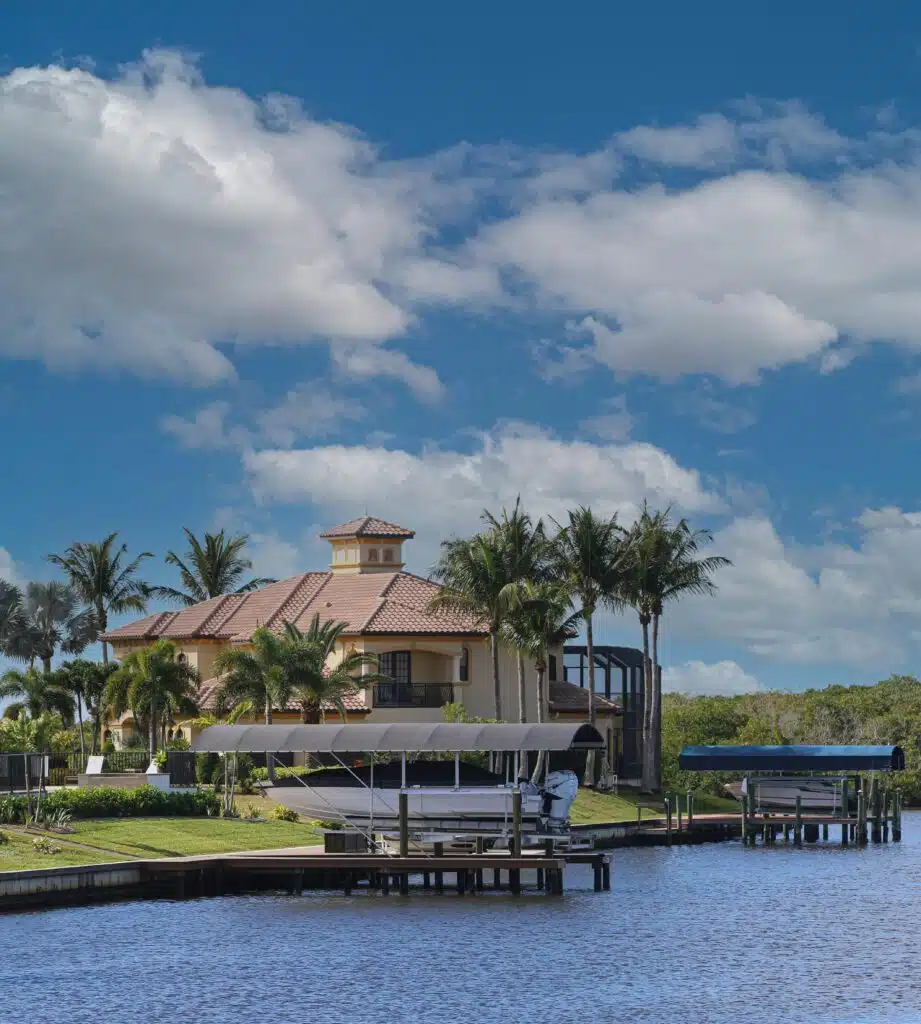 Beautiful waterfront home with boats and palm trees under clear skies in Cape Coral, Florida.