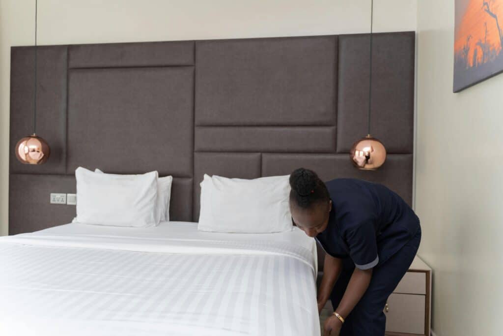 Hotel Staff Member preparing a bed A hotel staff member prepares a bed in a sleek, modern hotel room with copper accents.