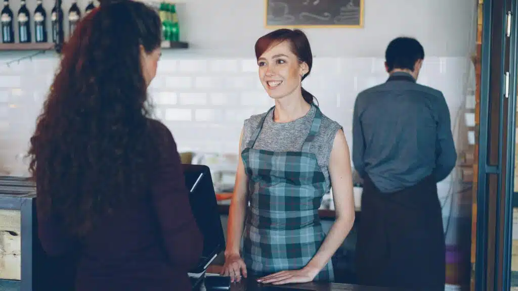 Commercial pest control services for Fort Myers businesses A barista with a plaid apron smiles while interacting with a customer at a café counter.