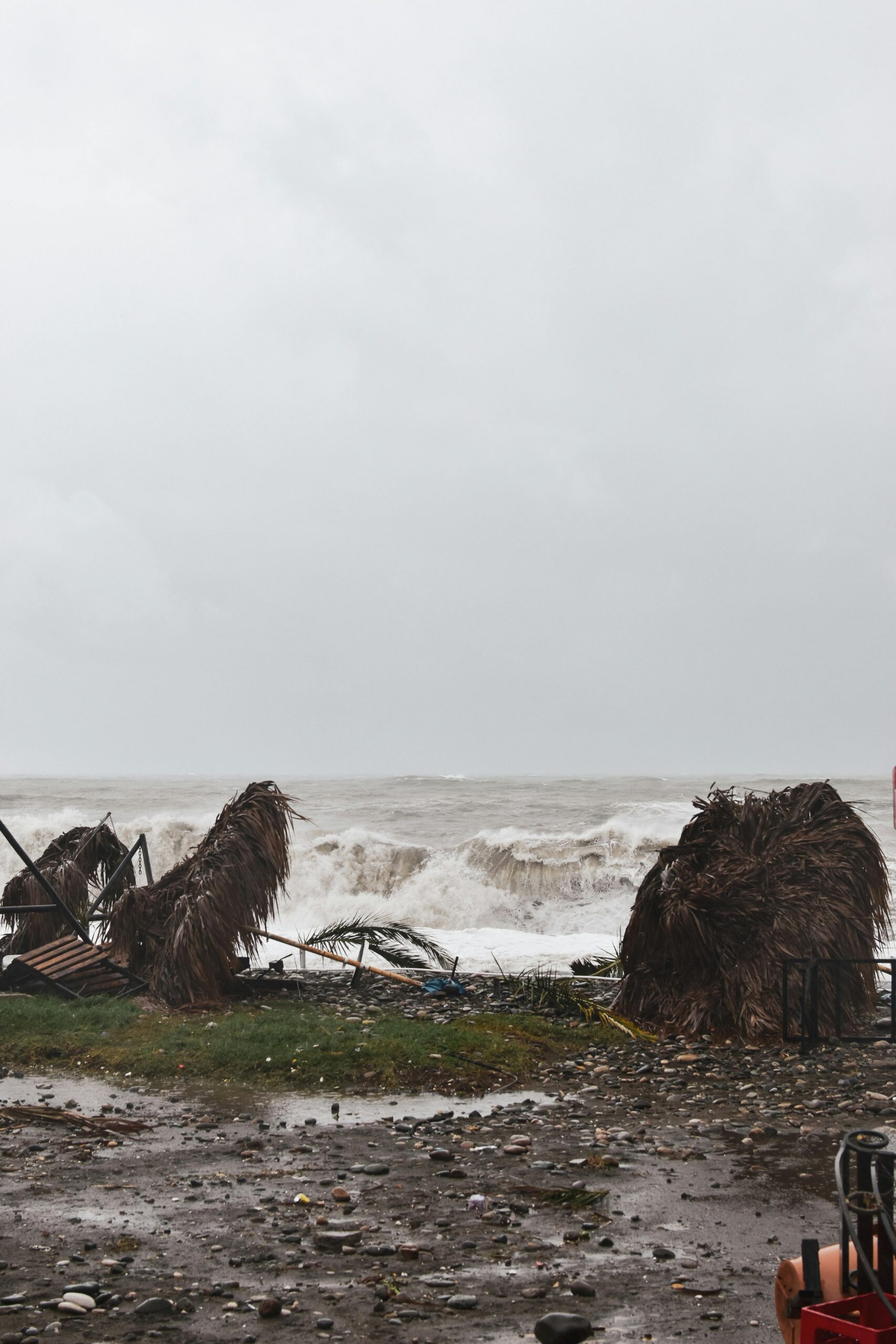 Debris and destruction on a beach after a hurricane with waves crashing ashore, showcasing nature's power.