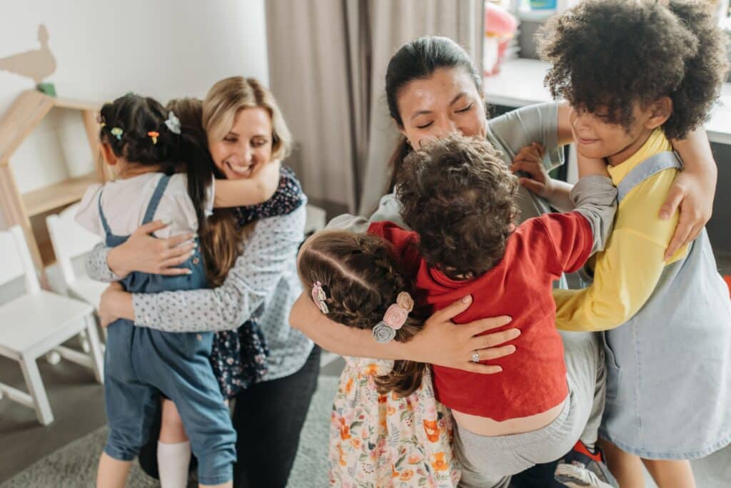 pexels-photo-8441849-8441849 Children and women sharing a heartwarming group hug indoors, expressing love and diversity.