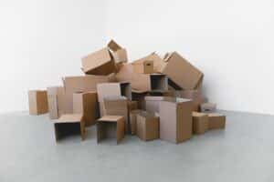 Pile of cardboard containers prepared for relocation on floor at home in daylight on white background